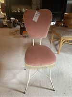 Front view of MCM vanity chair with pink upholstery and cream-colored metal base.