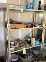 Full view of metal shelving unit with multiple shelves containing garden tools, cleaning supplies, extension cords, fire extinguisher, propane canister, and various containers.