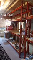 Full view of red steel shelving unit assembled in basement showing four levels of plywood shelves