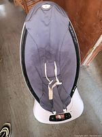 Full view of the baby swing seat showing black fabric and harness setup.