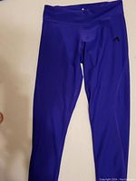 Front view of purple Adidas women's pants showing the Adidas logo on the left thigh area.