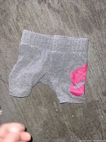 Front view of grey baby Nike shorts with pink logo.