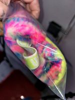 Photo of baby Ugg boot showing vibrant tie-dye interior lining and neon yellow heel tab with 'UGG' branding.