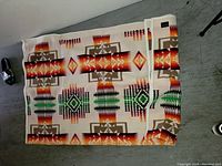 Patterned blanket with geometric design folded on floor
