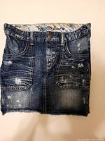 Front view of the denim skirt showing distressed areas, front pockets and button closure.