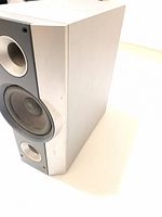 Front angled view of silver rectangular speaker showing woofer cone and part of speaker cabinet sides