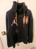 Front view of the black Jordan Jumpman hoodie with large color gradient Jumpman logo and yellow drawstrings.