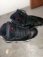 Pair of black Jordan basketball shoes with red Jumpman logo on tongue, showing side and top views.