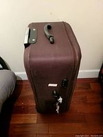 Brown soft-sided suitcase showing side handles, zipper, and combination lock