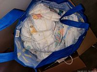 Photo showing a blue tote bag filled with new baby diapers featuring cartoon characters.