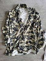 Front view of the women's camouflage long sleeve shirt, laid flat showing the collar, button-up front, and the camouflage print clearly.