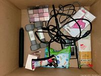 Top view of a lot with dumbbells, makeup lipsticks, razors, wipes, lotion, packaged noodles, and miscellaneous items.