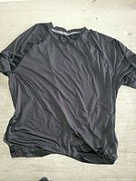 Full view of black Reebok t-shirt, laid flat showing front side and short sleeves.