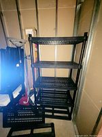 Black plastic modular shelving unit consisting of four shelves assembled in place.