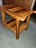 Side view of wooden side table showing slatted top, four legs, and lower slatted shelf.