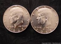Obverse view of two silver Kennedy dollar coins showing John F. Kennedy bust, dates 1967 and 1968, inscriptions LIBERTY, IN GOD WE TRUST.