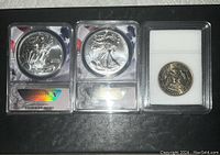 Three slabbed coins: two American Silver Eagles and one Kennedy half dollar