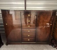 Front view of dark wood antique dresser with 6 center drawers and 2 cabinet doors with circular brass handles