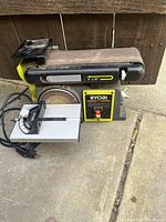 Front side view showing full belt sander, power switch and aluminum work table with angle gauge.