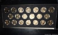 Overhead view of 20 silver-toned coins in plastic display case.