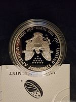 Reverse of American Silver Eagle coin showing heraldic eagle with shield, olive branch, arrows and 13 stars; inscriptions 'UNITED STATES OF AMERICA', '1 OZ. FINE SILVER—ONE DOLLAR'.