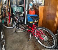 Side view of the tandem bike showing both seats, frames, pedals, and front handlebar.