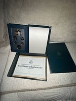 Folder open showing six proof coins and Certificate of Authenticity in lower compartment