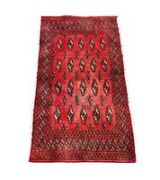 Single small rectangular Turkmen backrest rug with red field and dark geometric guls pattern with detailed border.