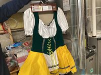 Full view of the Bavarian Beer Maid Costume hanging, showing the green bodice, white puffed sleeves, yellow skirt and decorative lace-up front.