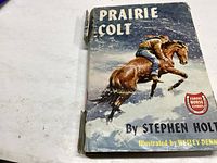 Front and top view of the Prairie Colt book showing the dust jacket illustration of a man riding a horse and the title and author details.