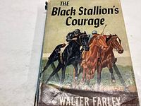 Front cover of The Black Stallion's Courage book showing illustrated horses racing.