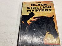 Front cover of The Black Stallion Mystery book showing a silhouetted boy riding a horse against a sunset background, title text at the top.