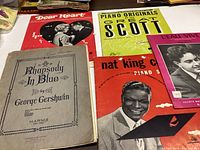 Five vintage sheet music books laid out showing titles and cover art.