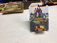 Photo showing unopened Hot Wheels Beatles Yellow Submarine die-cast car in original packaging with colorful Beatles artwork background on card.