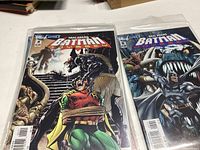 Comic books displayed in plastic sleeves, featuring Batman and Robin with textured backgrounds and dynamic poses.