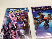 Justice League comic with multiple heroes in dynamic action poses on cover in plastic sleeve