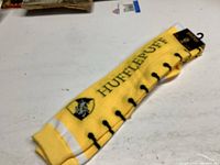 Photo showing full pair of yellow socks laid flat with Hufflepuff name and house crest visible on the side.