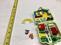 Open playset showing interior rooms and two small Pokémon figures alongside a Pokémon Center arch sign.