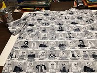 T-shirt laid flat showing all-over print of RuPaul's Drag Race All Stars queens in black and white with names and captions