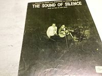Photo of sheet music cover for 'The Sound of Silence' showing Simon and Garfunkel sitting together, holding guitar and microphone, with text including song title, artist and composer details.