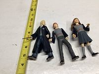 Three Harry Potter figures arranged horizontally next to a tape measure showing approximately 5-6 inches in height.