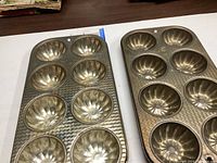 Two vintage Bake Rite muffin tins shown side by side, each with 12 fluted muffin cups made of metal with a textured finish.