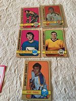 Five 1972-73 O-Pee-Chee hockey cards laid out on a surface showing player name and team including Phil Esposito and others.