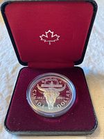 Front side of the silver coin showing buffalo skull and Regina commemorative design in protective capsule within red velvet case.
