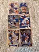 Six gold border baseball cards laid out on a fabric surface, showcasing Toronto Blue Jays players including Devon White, Jack Morris, Roberto Alomar, Joe Carter, Kelly Gruber, and Tom Henke.
