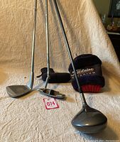 Three right-handed golf clubs: Titleist 975D driver, PGA T-Line XVI putter, Plus wedge. Includes two Titleist head covers.