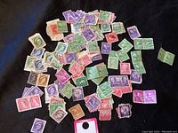 Wide spread of assorted used stamps from USA and Canada in various colors and denominations scattered on black background.