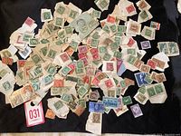 Wide pile of various small Canadian postage stamps, many torn from envelopes or paper, including green, red, brown, purple and blue colors, all with cancellation marks.