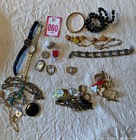 Overview of various jewelry items including watches, bracelets, rings, earrings, and necklaces on fabric background