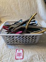 Photo of a white plastic basket containing multiple pliers with rubber coated handles of various colors including red, yellow, pink, and black.